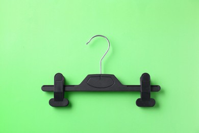 Photo of Black hanger with clips on light green background, top view