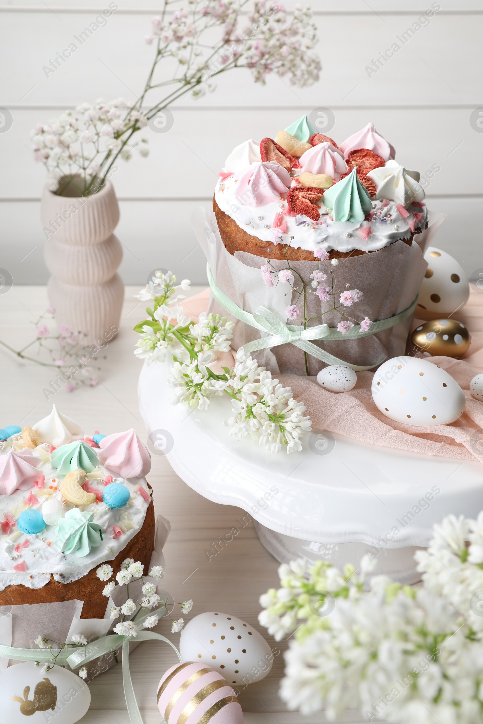 Photo of Traditional Easter cakes with meringues and painted eggs on white wooden table