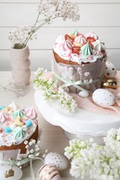 Traditional Easter cakes with meringues and painted eggs on white wooden table