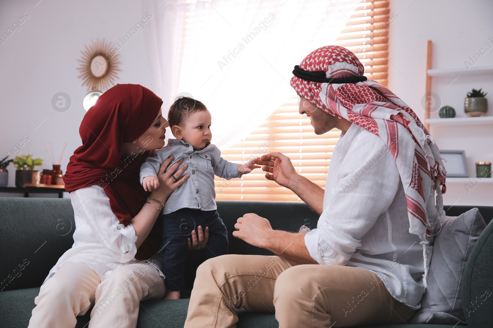 Photo of Happy Muslim family with little son in living room