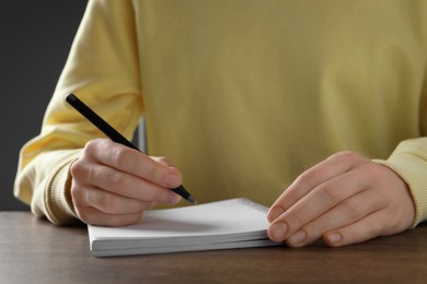 Photo of Woman with pen and notepads at wooden table, closeup