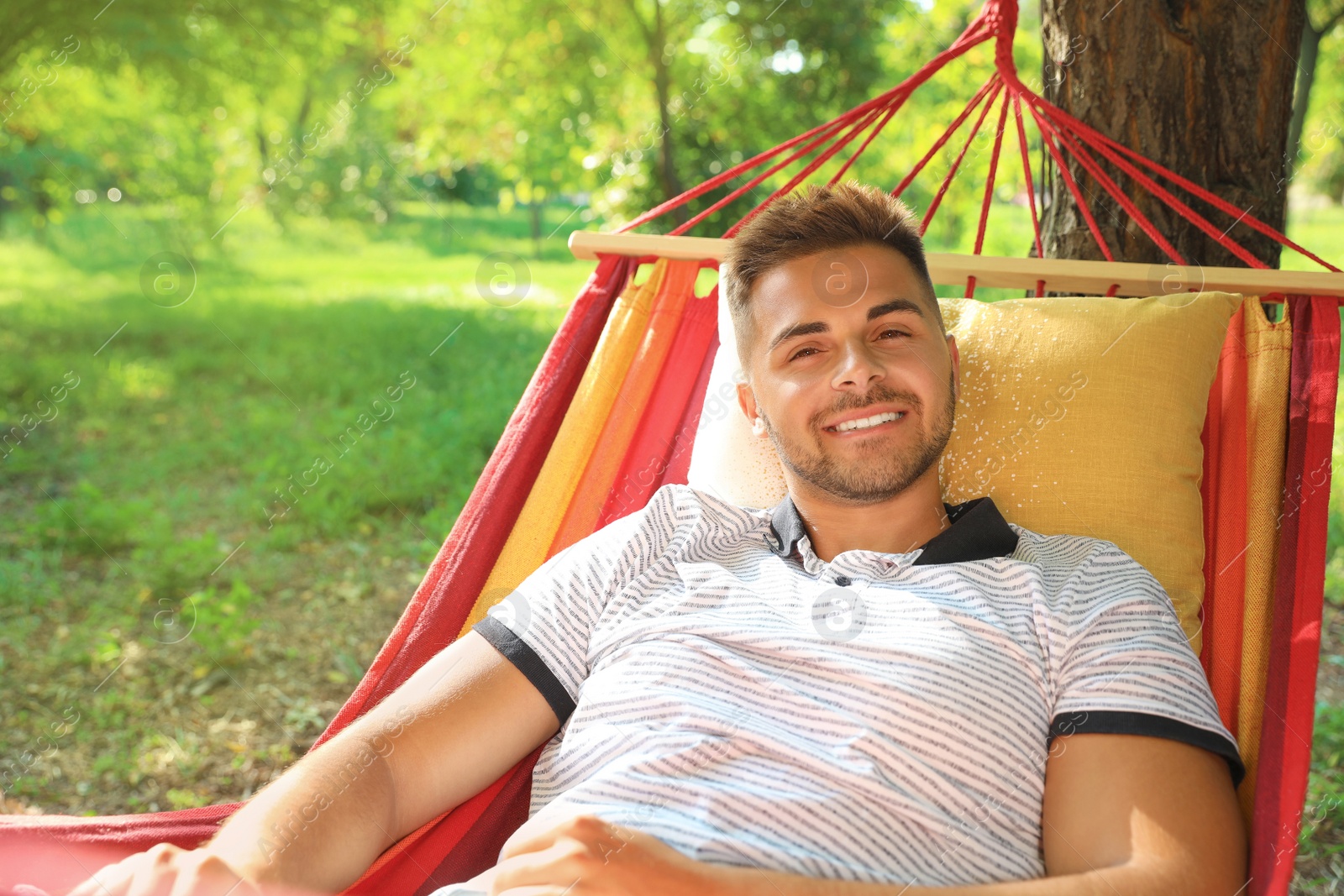 Photo of Young man resting in comfortable hammock at green garden