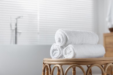 Photo of Rolled bath towels on wicker table in bathroom. Space for text