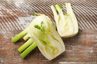 Whole and cut fennel bulbs on wooden table, top view