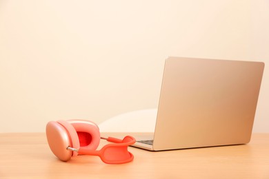 Photo of Modern laptop and headphones on wooden table. Space for text