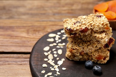 Photo of Stack of tasty granola bars on wooden table, closeup. Space for text