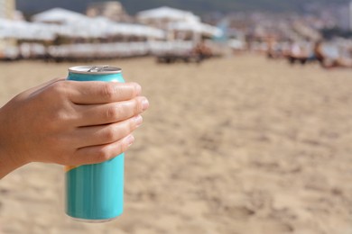 Photo of Woman holding aluminum can with beverage on beach, closeup. Space for text