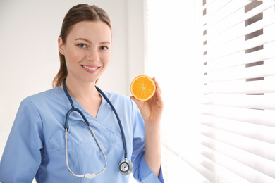 Nutritionist with orange near window in office