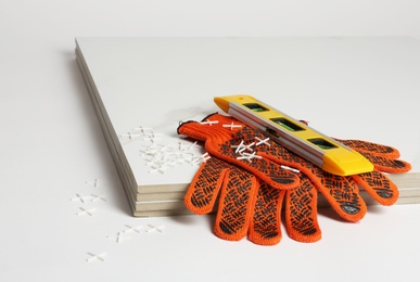 Ceramic tiles with gloves and level on white background