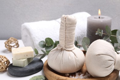 Spa composition with herbal massage bags and eucalyptus branches on white table