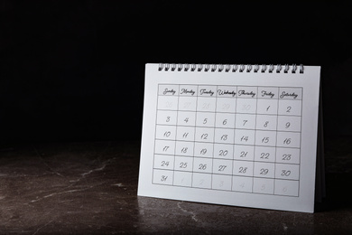 Photo of Paper calendar on stone table, space for text. Planning concept