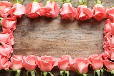 Frame made with beautiful roses on wooden table