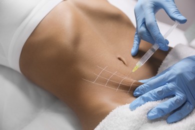 Photo of Young woman getting belly injection in salon, closeup