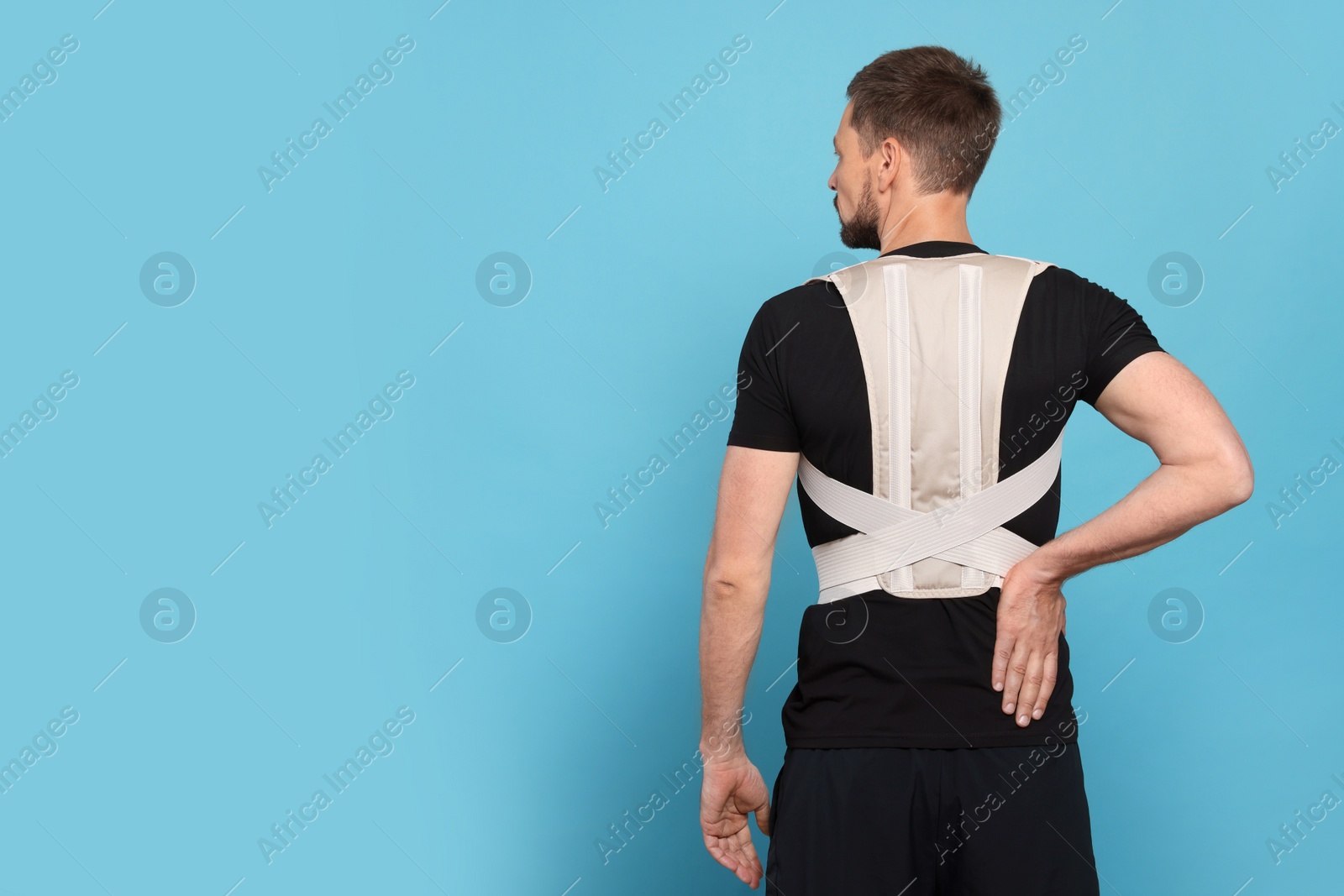 Photo of Man with orthopedic corset on blue background, back view. Space for text