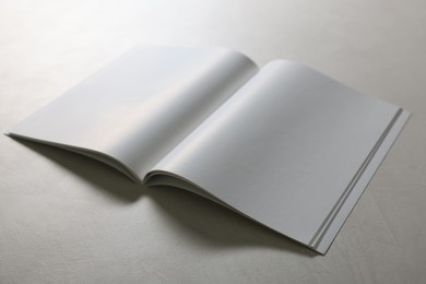 Photo of Open notebook with blank pages on grey textured table, closeup. Mockup for design