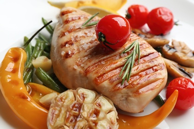 Photo of Tasty grilled chicken fillet with vegetables on plate, closeup