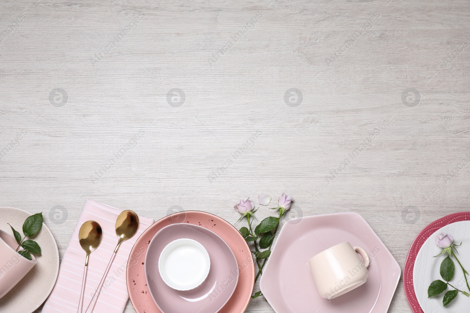 Photo of Flat lay composition with beautiful dishware and roses on white wooden table. Space for text