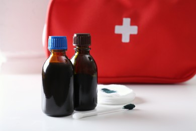 Photo of Bottles of brilliant green, cotton bud and pads on white table. Space for text