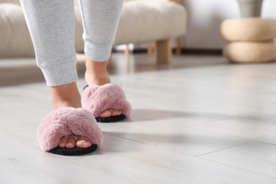 Photo of Woman wearing soft slippers at home, closeup of legs