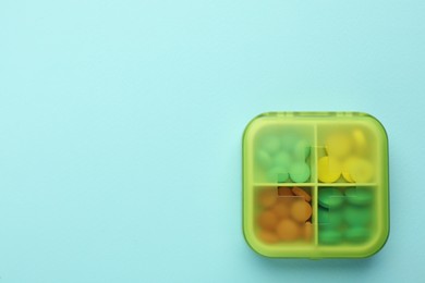 Pill box with medicaments on turquoise background, top view. Space for text
