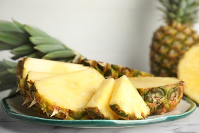 Photo of Plate with tasty cut pineapple on table, closeup