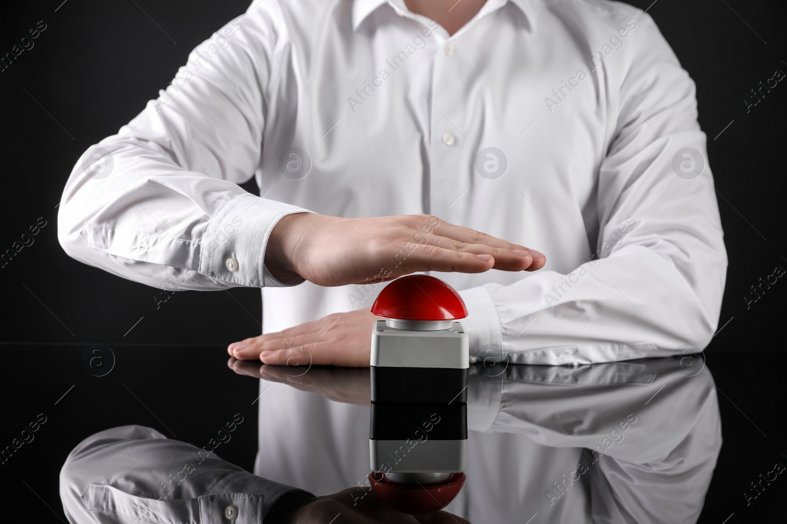Photo of Man pressing red button of nuclear weapon on black background, closeup. War concept
