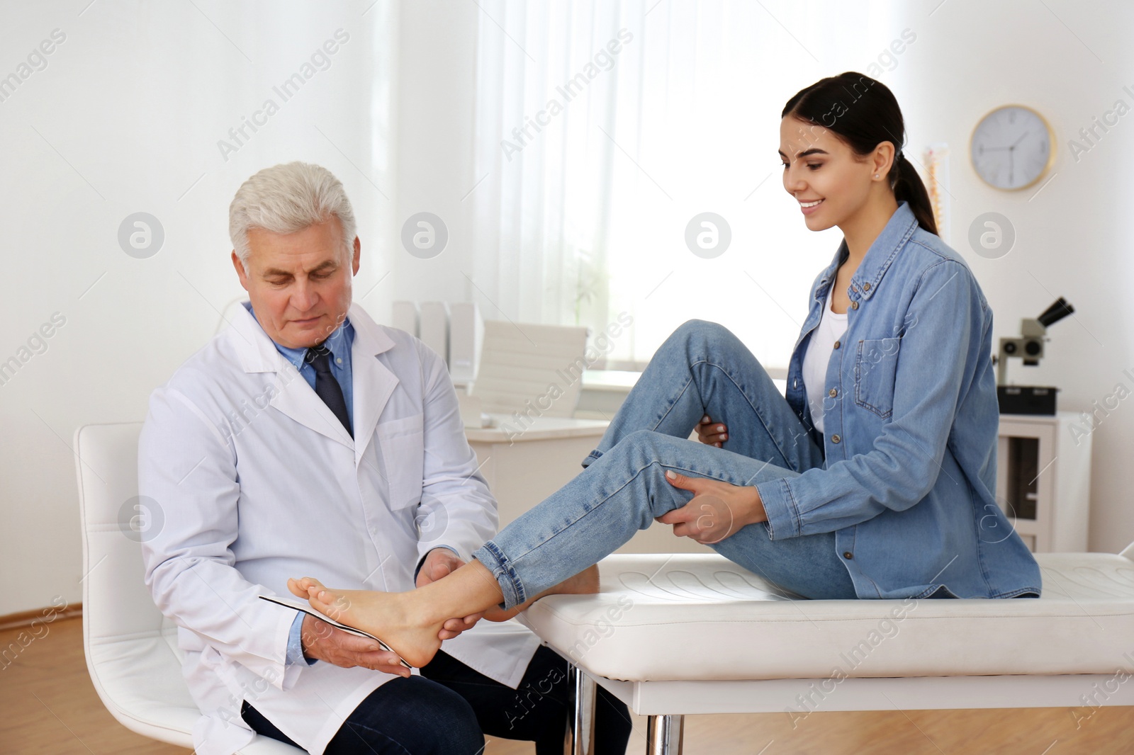 Photo of Male orthopedist fitting insole on patient's foot in clinic