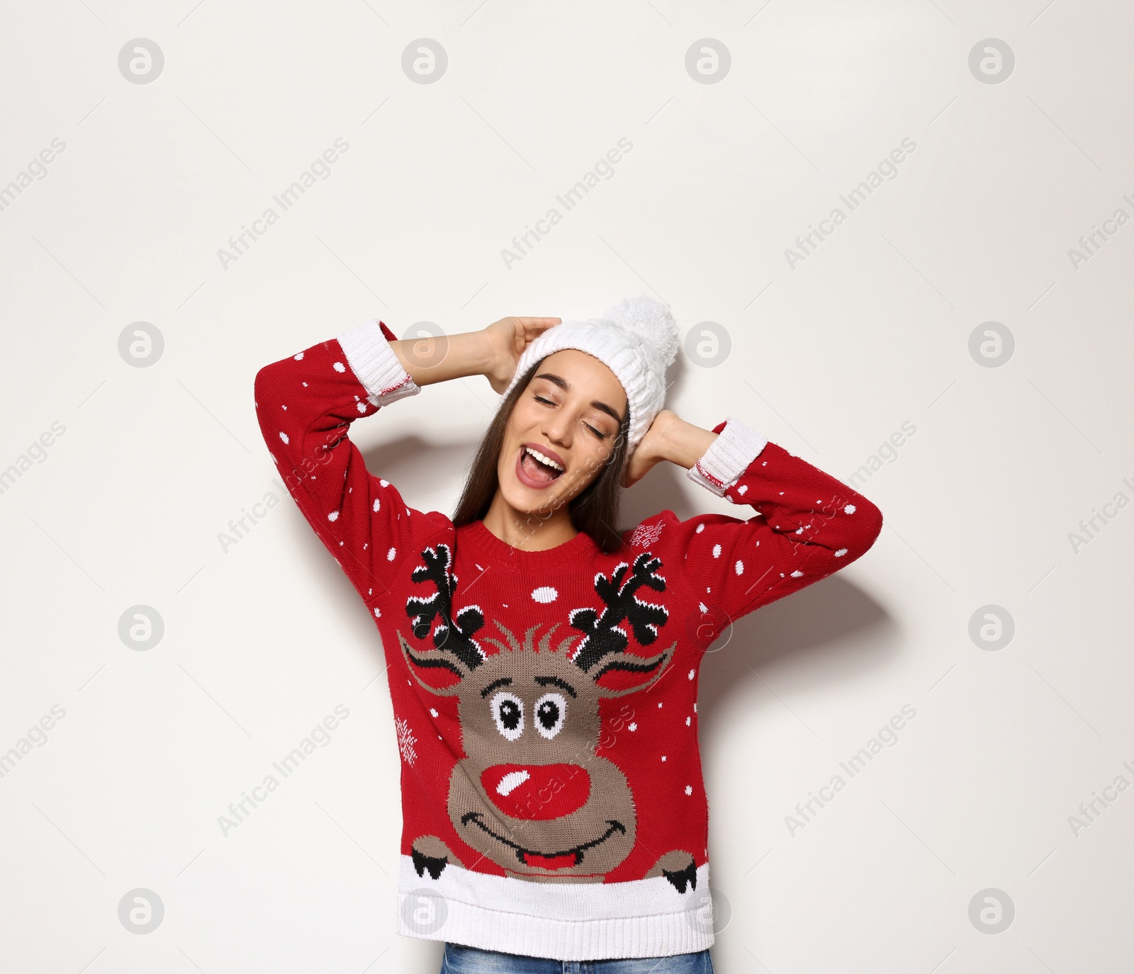 Photo of Young woman in Christmas sweater and knitted hat on white background