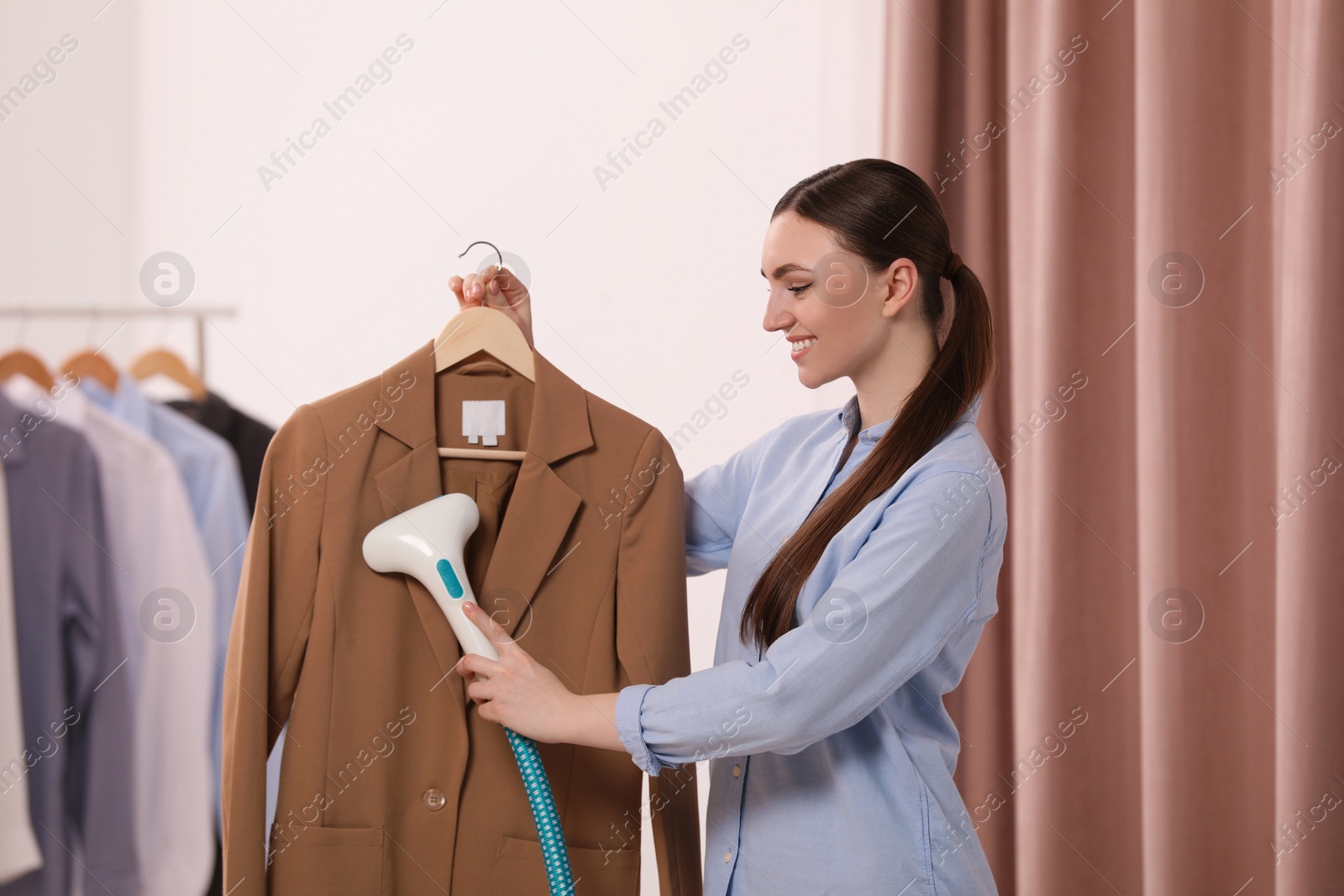 Photo of Woman steaming jacket on hanger in room