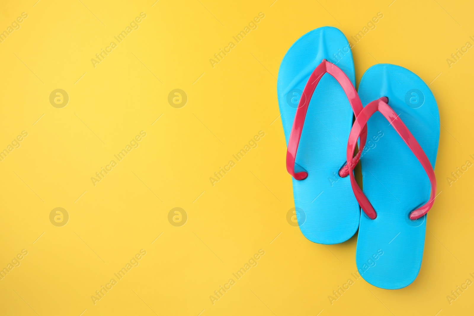 Photo of Stylish flip flops on yellow background, flat lay with space for text