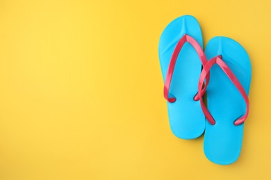 Photo of Stylish flip flops on yellow background, flat lay with space for text