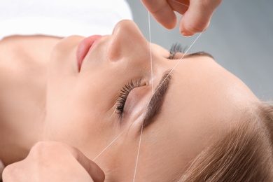 Young woman having professional eyebrow correction procedure in beauty salon