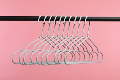 Photo of Empty clothes hangers on rack against pink background