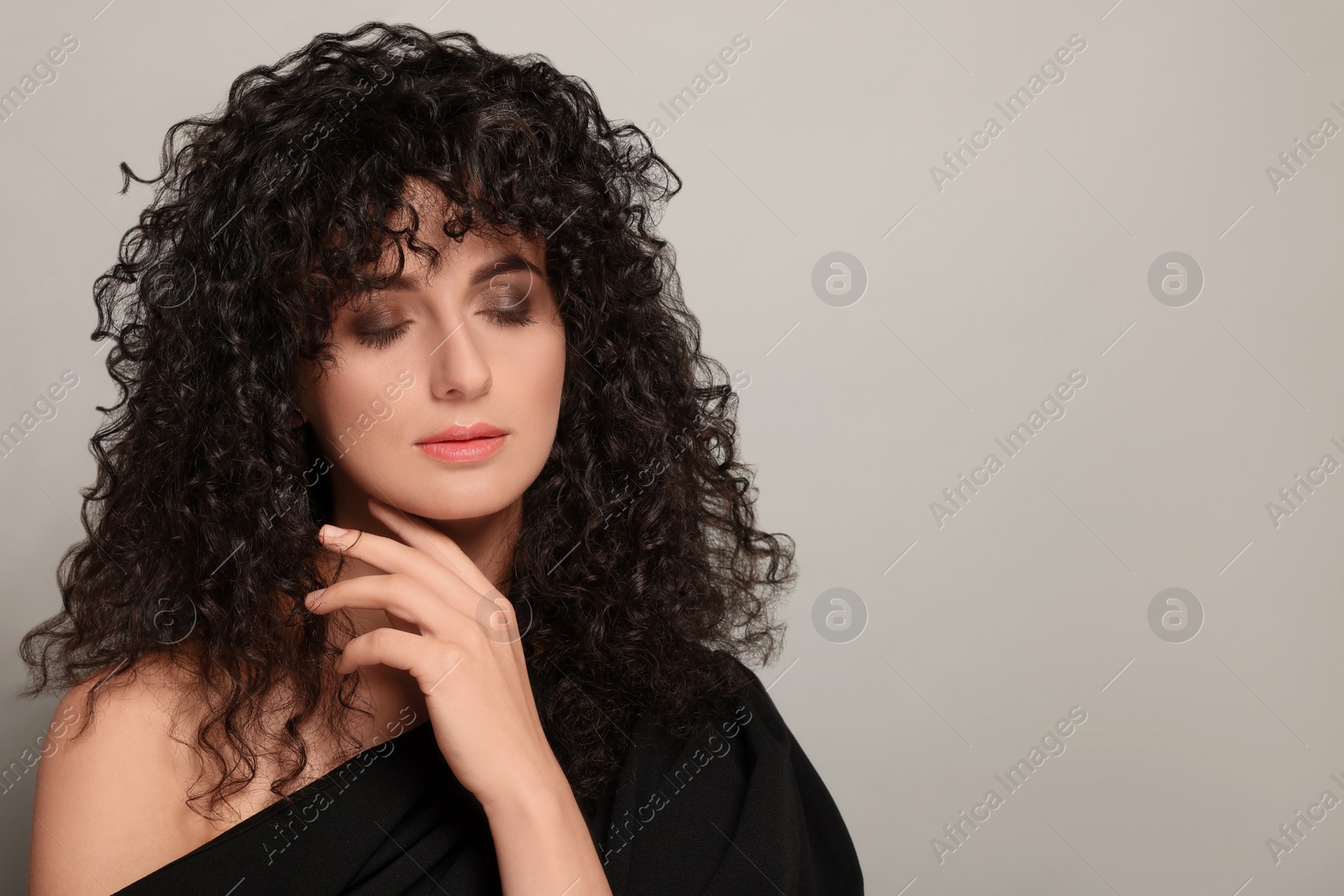 Photo of Beautiful young woman with long curly hair on light grey background. Space for text