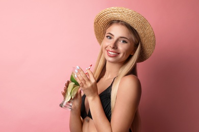 Pretty young woman wearing stylish bikini with cocktail on pink background