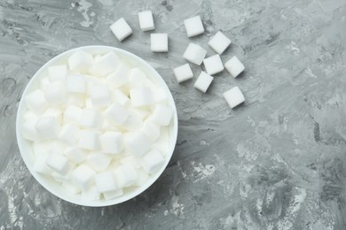 White sugar cubes in bowl on grey table, top view. Space for text
