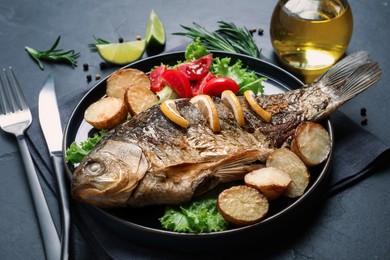 Photo of Tasty homemade roasted crucian carp served on black table. River fish