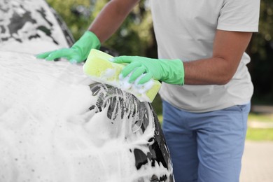 Man washing car with sponge outdoors, closeup