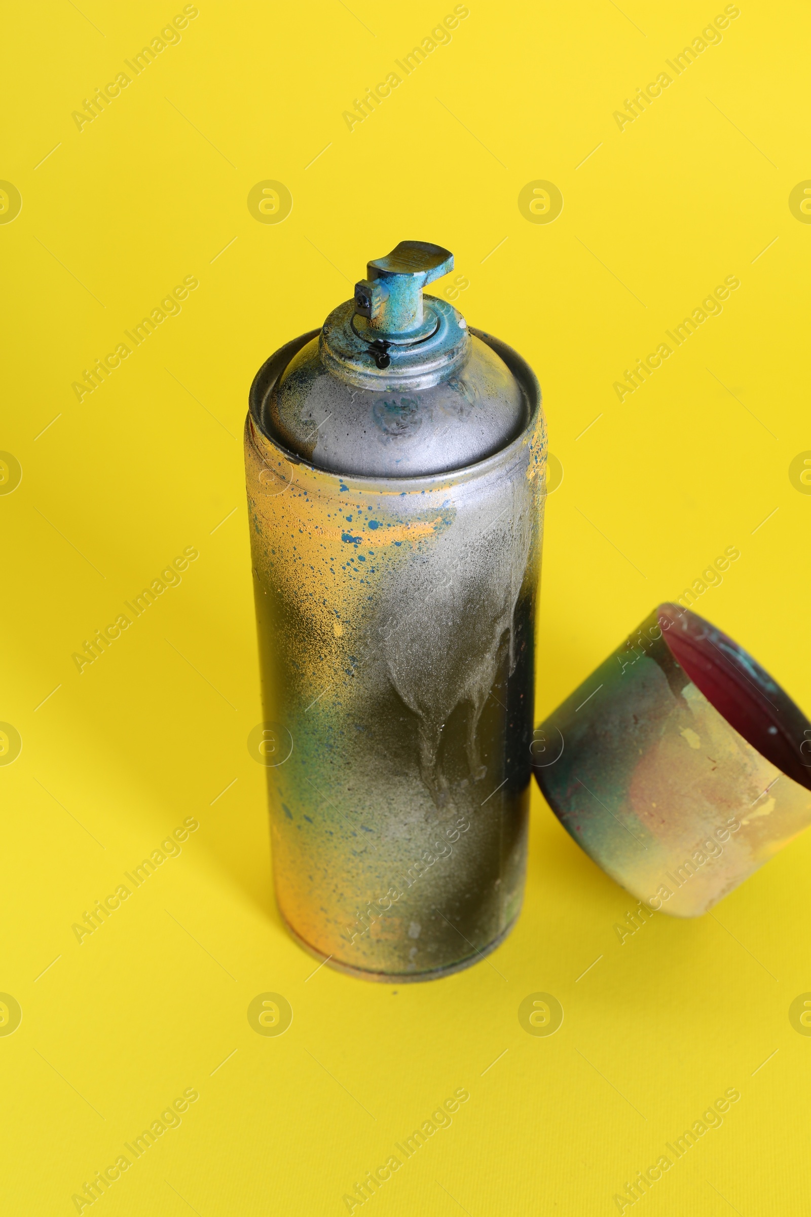 Photo of One spray paint can with cap on yellow background