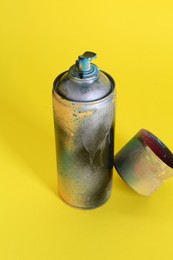 One spray paint can with cap on yellow background