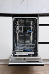 Open clean empty dishwasher in kitchen. Home appliance