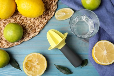 Photo of Citrus reamer, fresh lemons and limes on light blue wooden table, flat lay
