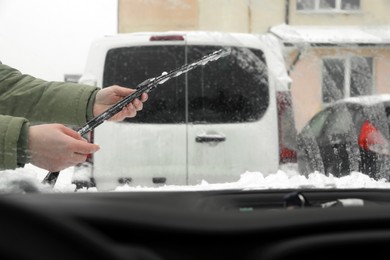 Photo of Closeup of woman cleaning wiper blade from snow, view from inside