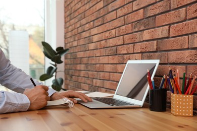 Photo of Man drawing in notebook at online lesson indoors, closeup. Distance learning