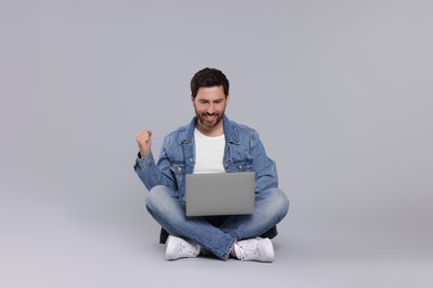Photo of Emotional man with laptop on light grey background