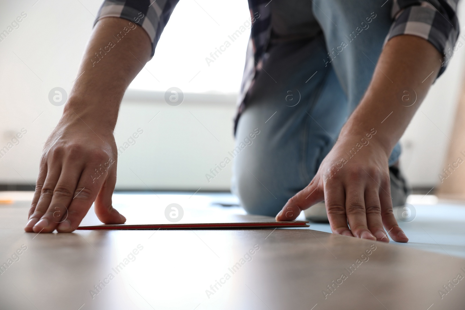 Photo of Worker installing laminated wooden floor indoors, closeup