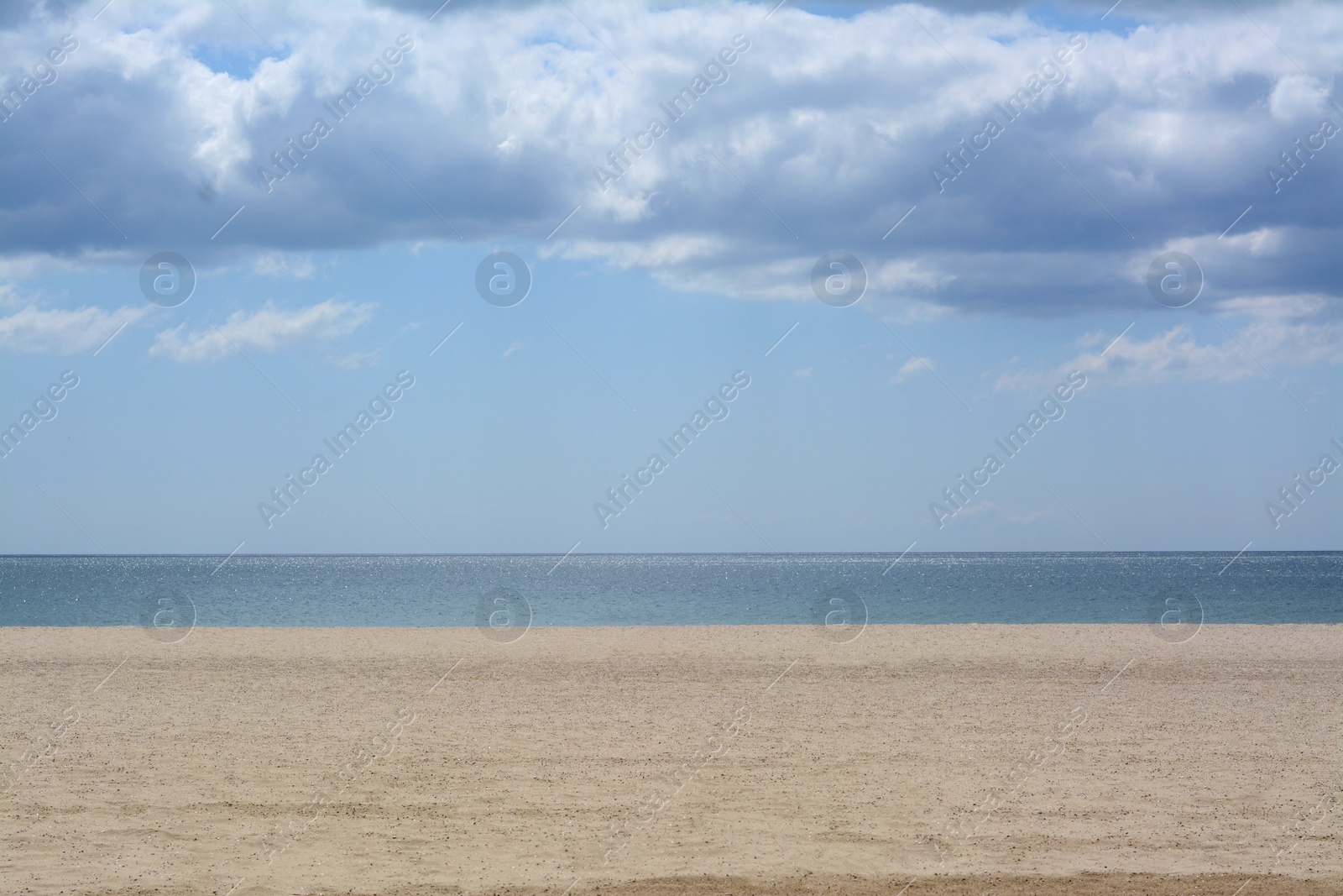 Photo of Picturesque view of sandy beach near calm sea on cloudy day