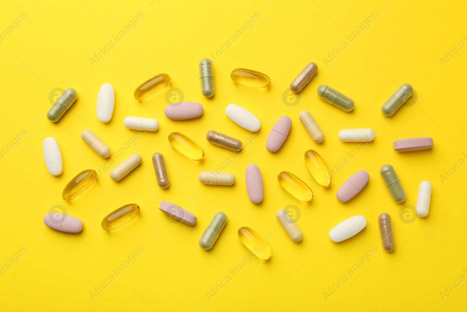 Photo of Different vitamin pills on yellow background, flat lay