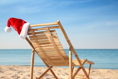 Sun lounger with Santa's hat on beach. Christmas vacation