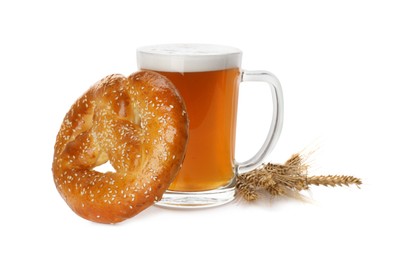 Tasty freshly baked pretzel, mug of beer and spikelets on white background